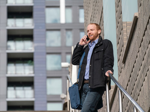 Man on outdoor stairs using mobile phone to access small business phone system