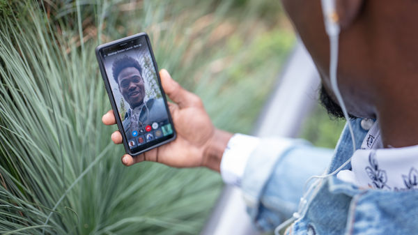 Man outdoors using 8x8 video conferencing solutions on his smartphone to collaborate with teammate